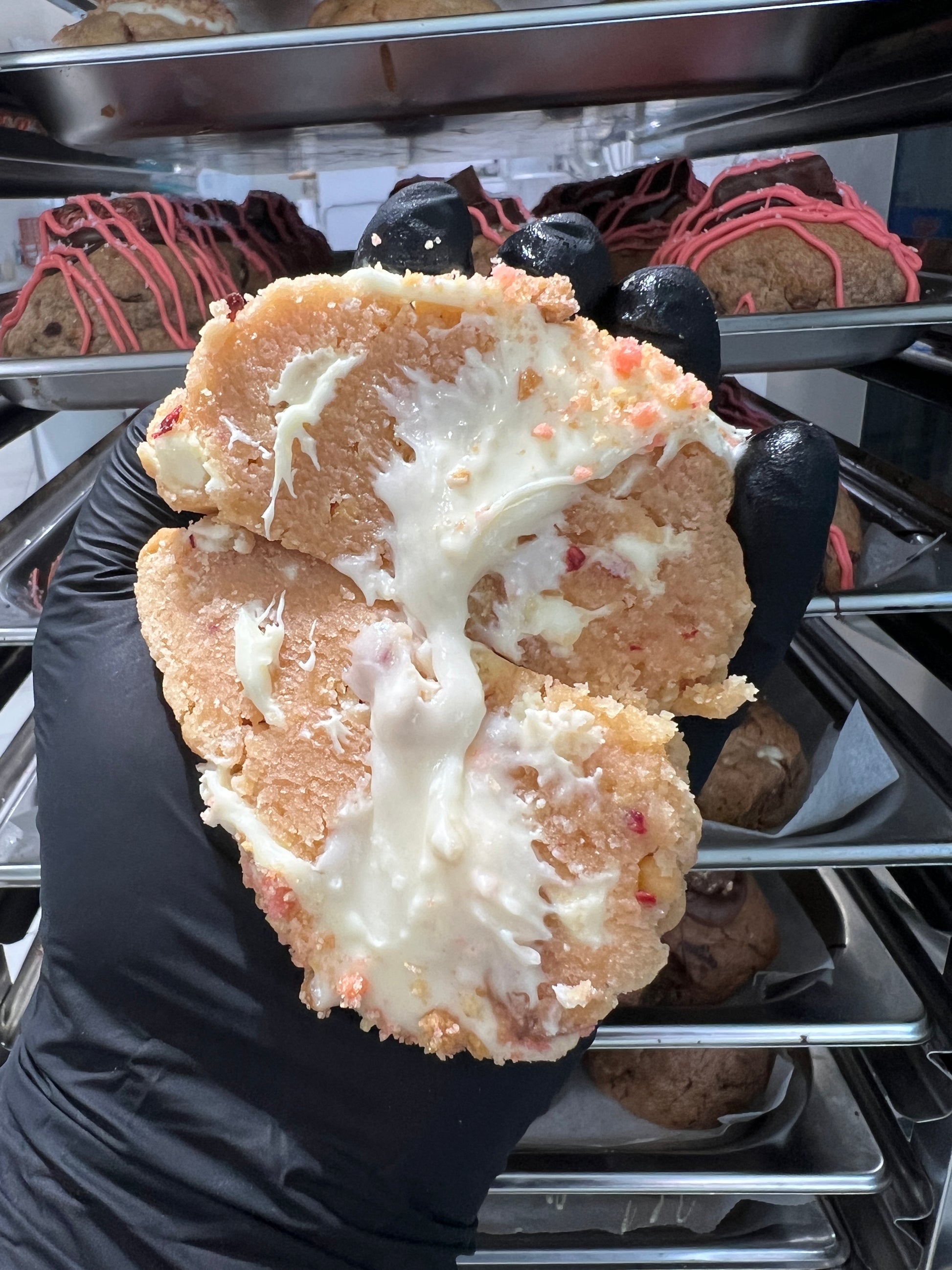 Close-up of the Strawberry Shortcake Loaded Cookie with rich cheesecake frosting spilling from the centre, topped with white chocolate and strawberry crumble.