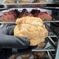 Side view of the Strawberry Shortcake Loaded Cookie, revealing the creamy cheesecake filling and strawberry crumble within the soft, golden cookie.