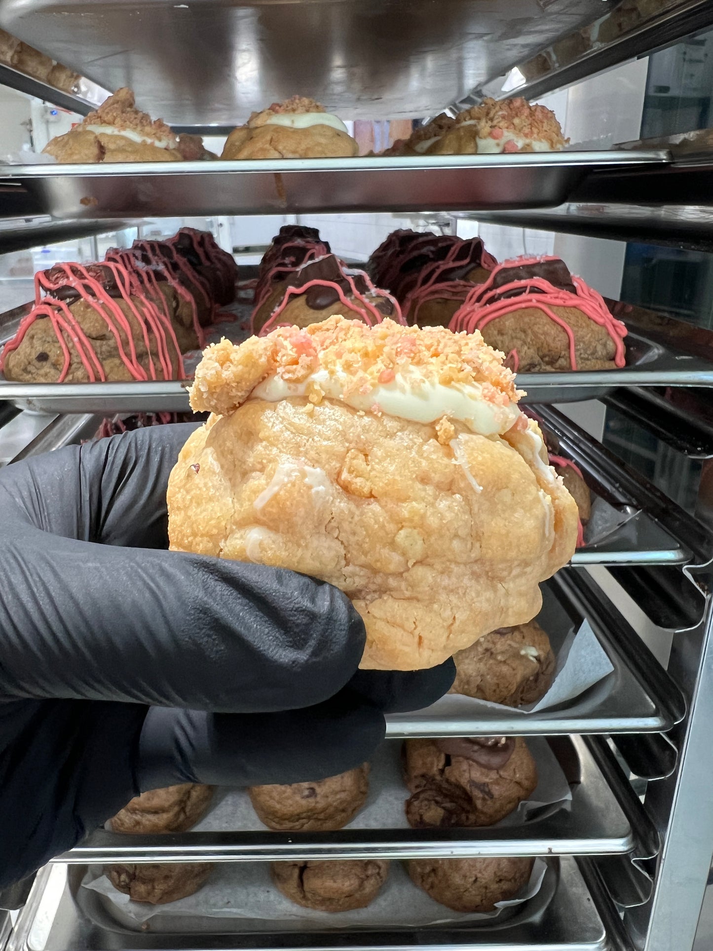 Side view of the Strawberry Shortcake Loaded Cookie, revealing the creamy cheesecake filling and strawberry crumble within the soft, golden cookie.