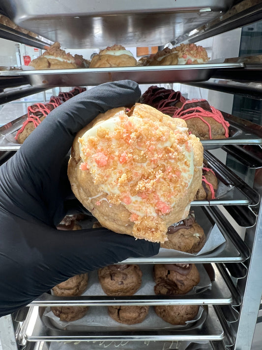 Top view of our Strawberry Shortcake Loaded Cookie, showcasing the white chocolate drizzle, strawberry crumble, and cheesecake frosting peeking through.